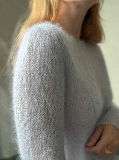 a woman with red hair wearing a white sweater