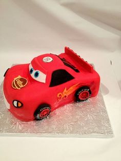 a red car cake sitting on top of a glass plate covered in frosted icing