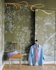 a room with green wallpaper and a chair next to the closet door that has a blue shirt on it