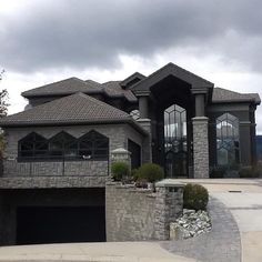 a large house with a stone wall and two garages on the side of it