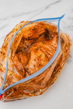 a plastic bag filled with chicken sitting on top of a white marble countertop next to a red and blue toothbrush