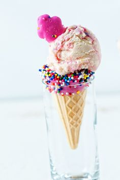 two scoops of ice cream with sprinkles in a glass on a table