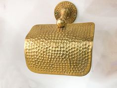 a gold toilet paper holder hanging on a wall with a white back drop in the background