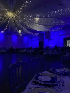 a banquet hall with blue lighting and white table cloths