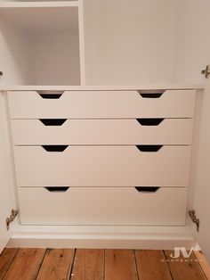 a white dresser with black handles and drawers in a room that has wood floors on the floor