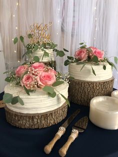 two wedding cakes with pink flowers and greenery sit on a table next to each other