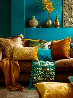 a living room filled with lots of different colored pillows and blankets on top of a couch