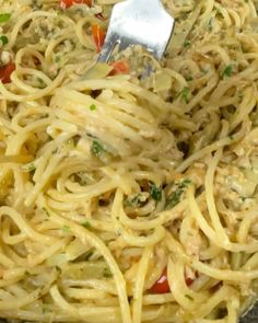 a fork is stuck into some pasta in a skillet