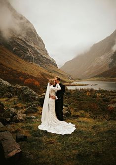 a bride and groom kissing in the mountains