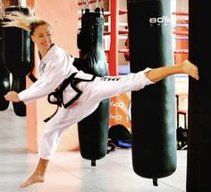 a woman is practicing kickbox moves in a gym with punching gloves on the floor