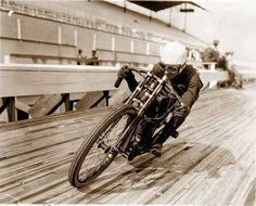 a man riding on the back of a motorcycle down a wooden ramp