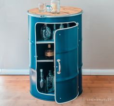 a blue barrel with bottles in it sitting on top of a hard wood floor next to a wall