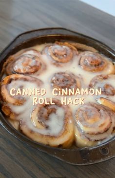 a pan filled with cinnamon rolls on top of a wooden table next to a sign