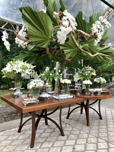 a table topped with lots of white flowers next to a large green leafy tree