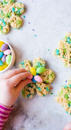 a child is picking up some kind of cookie from the table with other cookies on it