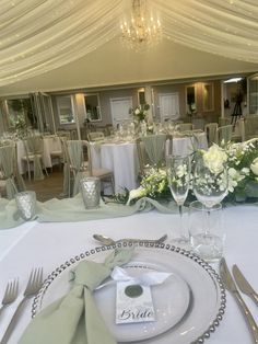 a table set up for a wedding reception with flowers and place settings on the table