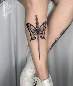 a woman's leg with a knife and butterfly tattoo on the side of her leg