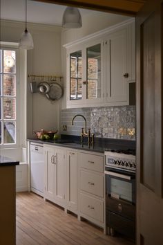 a kitchen with white cabinets and black counter tops in front of a large window that looks out onto the street