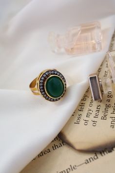 This elegant ring features a central green stone surrounded by sparkling cubic zirconia, adding a touch of glamour to any ensemble. Its versatility makes it perfect for complementing a variety of outfits and styles. Finish: 22KT Gold Plating Material: Silver, Copper Alloy, Polki Color: Green Size: One Size Closure Type: Adjustable Box Contains: 1 Ring Luxury Green Crystal Ring In Open Ring Style, Elegant Crystal Ring With Stones For Formal Occasions, Elegant Open Crystal Ring With Stones, Green Diamond Open Ring, Elegant Crystal Open Ring With Stones, Elegant Party Rings With May Birthstone, Round Emerald Party Ring, Elegant Open Crystal Ring, Elegant May Birthstone Rings For Party