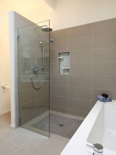 a bathroom with a walk in shower next to a white bathtub and tiled floor