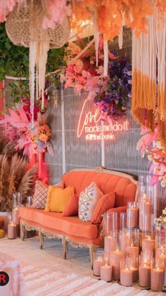 an orange couch sitting in front of a wall with candles and flowers hanging from it