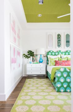 a bedroom with green and white decor on the ceiling, bedding and rugs