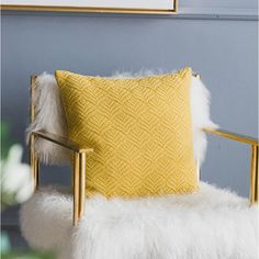 a yellow pillow sitting on top of a white chair next to a wall with pictures above it