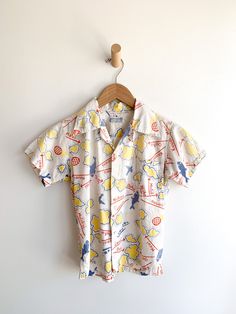 Darling cotton short sleeve Hawaiian Island motif shirt. Beautiful aging and fade. Fabric: CottonLabel: Watumull'sFit: XSEra: 1930/50’s Measurements: Bust 36" Shoulder 14" Sleeve 5.5" Sleeve hole opening (flat) 6" Length 21" Waist 34" Condition: Very good. One small hole on front and a bunch of small paint(?) dots on front (see photos). Collared Cotton Hawaiian Shirt With All-over Print, Pre-washed Short Sleeve Tops For Summer, White Cotton Hawaiian Shirt With All Over Print, White Cotton Hawaiian Shirt With Print, Cotton Camp Shirt With Retro Print, White Cotton Camp Shirt With All Over Print, Cotton Hawaiian Shirt With All Over Print, Retro Collared Short Sleeve Shirt With Graphic Print, Cotton Camp Shirt With Vintage Print