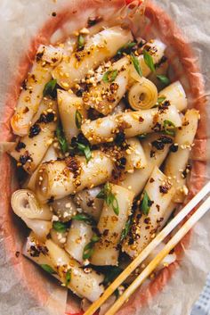 a bowl filled with noodles and chopsticks on top of a table