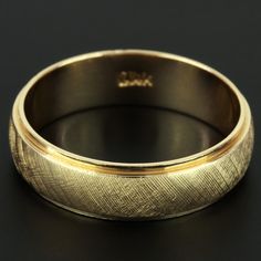 a gold wedding ring on a black surface