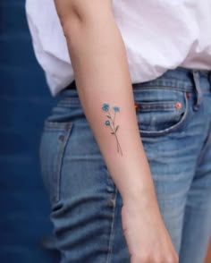 a small blue flower tattoo on the left arm