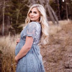 a pregnant woman in a blue dress is posing for a photo with her hands on her hips