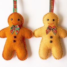 two felt gingerbread man and woman ornament hanging from twine on white background