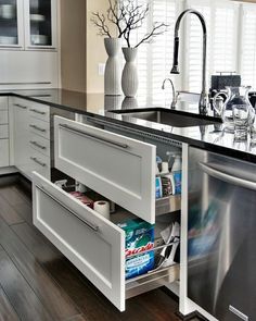 an open dishwasher in a kitchen next to a sink and counter with drawers