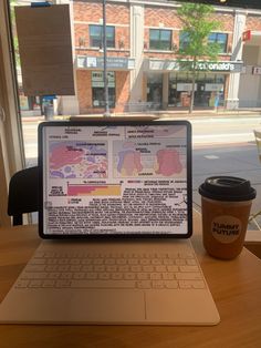 an open laptop computer sitting on top of a wooden table next to a cup of coffee