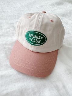 A baseball cap featuring a tennis club embroidery and an adjustable clasp for the perfect fit. Runs large recommended for ages 2+ Kitan Club Hats, Sporty Snapback Hat For Tennis, Sporty Snapback Baseball Cap For Tennis, White Baseball Cap For Tennis, White Tennis Baseball Cap, Casual Snapback Tennis Hat, Casual Summer Tennis Hat, Casual Baseball Cap With Curved Brim For Tennis, Casual Curved Brim Baseball Cap For Tennis