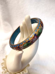 Vintage Chinese Champlevé Cloisonne bangle bracelet.   Flowers and leaves in raised enamel on a gilt base.  Raised enamel blue scalloped edge, rounded outside, flat blue enamel inside.   Older vintage piece (circa 1950s) in excellent condition.   No missing enamel. 1/2 inch wide, ¼  inch thick, 1 1/2 inch, 7 3/4 inch inner circumference. This process is the opposite of the cloisonné technique: instead of building up on the surface of the metal object,  the surface is gouged away, creating trough Antique Blue Bracelet As Gift, Antique Blue Round Bracelets, Collectible Enamel Bangle Jewelry, Blue Enamel Bangle Bracelets, Handmade Vintage Enamel Bangle, Vintage Enamel Bangle Jewelry, Vintage Handmade Enamel Bangle, Vintage Blue Bangle Bracelets, Blue Enamel Bangle