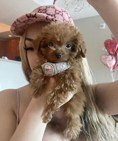 a woman holding a small dog in her mouth while wearing a pink hat and scarf