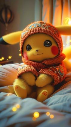 a stuffed animal wearing a hat and scarf sitting on a bed with lights in the background