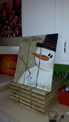 there are several books stacked on top of each other in the kitchen with snowmen painted on them