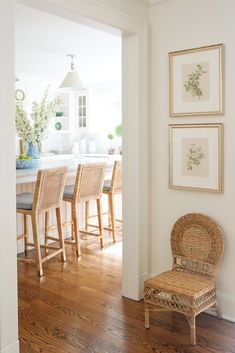 a dining room table and chairs with pictures on the wall above them in front of an open kitchen door