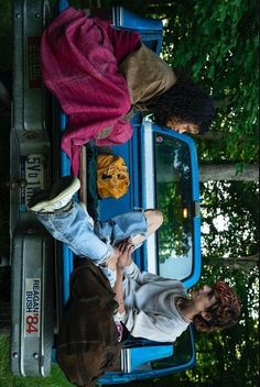 two people standing in the back of a blue truck