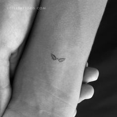 a small butterfly tattoo on the left wrist is shown in this black and white photo