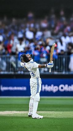 a man holding a cricket bat on top of a field in front of a crowd