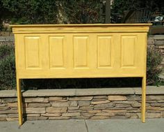 a yellow bed frame sitting next to a stone wall