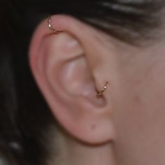 a woman's ear is shown with a tiny gold nose pin in the middle