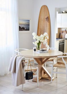 a surfboard is in the background behind a table with flowers and a purse on it