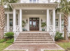 a large white house with palm trees in the front yard and steps leading up to it