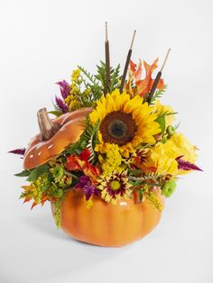 a pumpkin filled with lots of flowers on top of a table