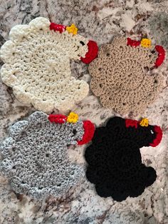 four crocheted sheeps are sitting on a marble surface with red, white and black ones